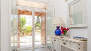 Una habitación con un escritorio blanco, una lámpara azul, un espejo y un florero con flores.