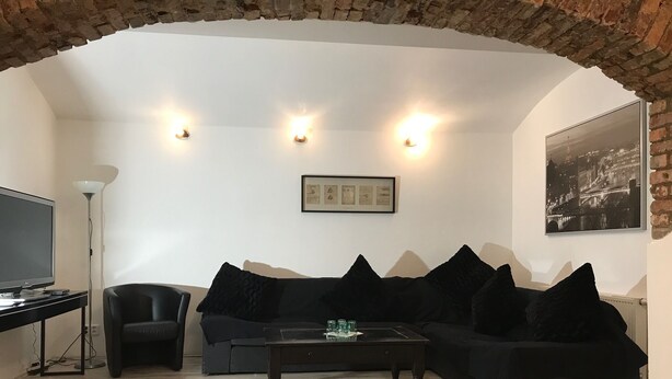 A living room with a black sofa, a coffee table, a TV, and a framed picture on the wall. - 3 Bed Flat - Sleeps 20 - Smoking Room - Wifi (Prague)