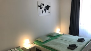 A neatly arranged bedroom with a single bed, two bedside tables, and a world map on the wall. - 3 Bed Flat - Sleeps 20 - Smoking Room - Wifi (Prague)