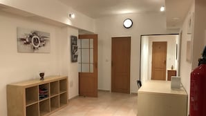 A hallway with a wooden door, a small table with a vase, and a wall-mounted light fixture. - 3 Bed Flat - Sleeps 20 - Smoking Room - Wifi (Prague)