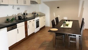 A compact kitchen with white cabinets, a stove, and a dining table with chairs. - 3 Bed Flat - Sleeps 20 - Smoking Room - Wifi (Prague)