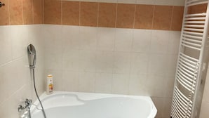 A bathroom with a white bathtub, a showerhead, and a white towel rack. - 3 Bed Flat - Sleeps 20 - Smoking Room - Wifi (Prague)