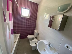 Une salle de bain équipée d’une baignoire, de toilettes, d’un bidet et d’un lavabo.
