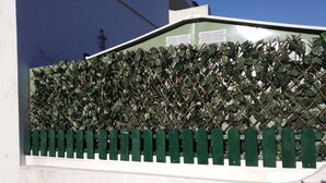 Een witte muur met een groene hek en een klimplantenwand.