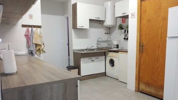 Een kleine keuken met een wasmachine, een koffiezetapparaat en een spoelbak.