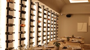 Un restaurante con una pared de vinos, mesas y sillas de madera.