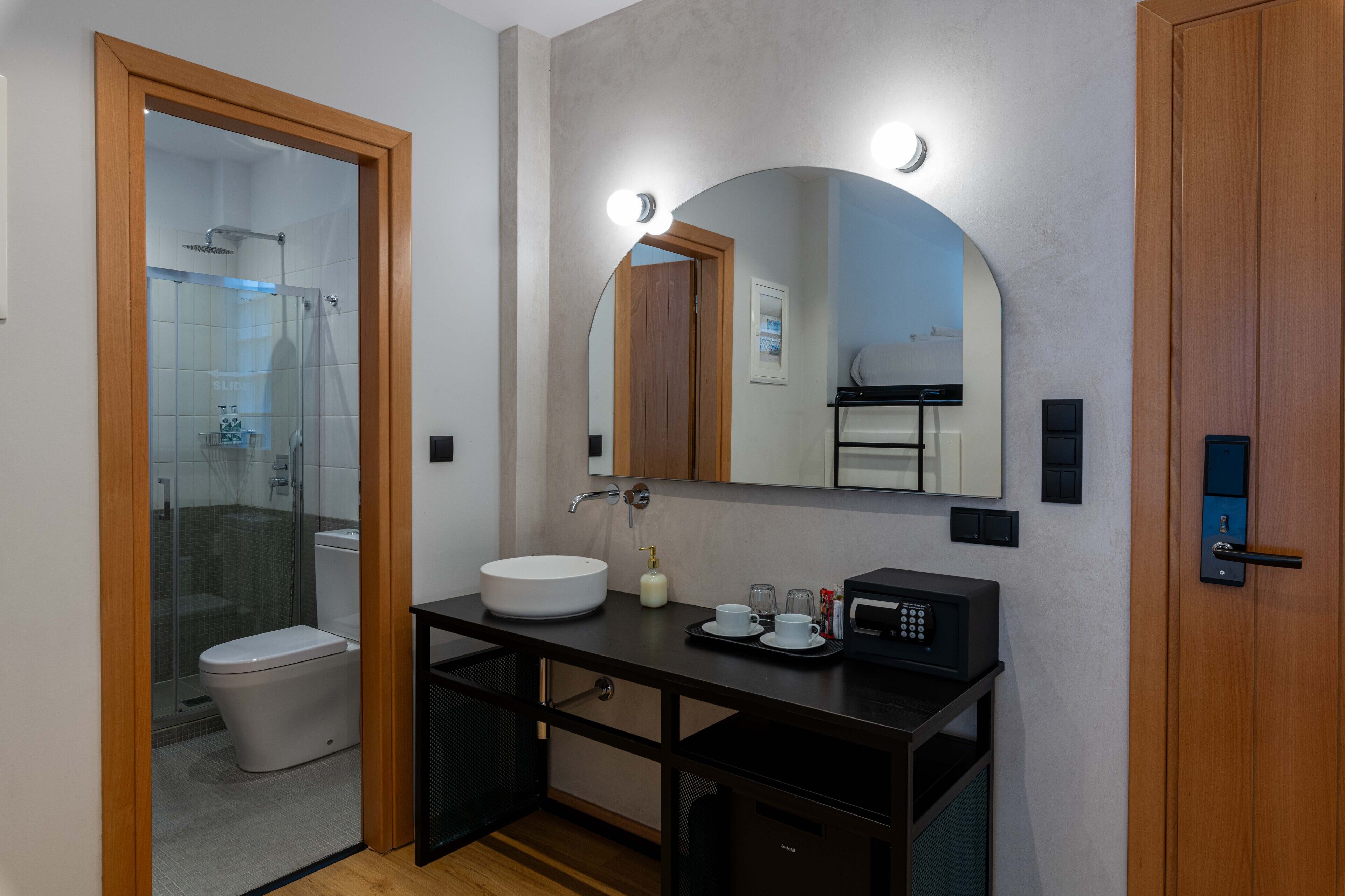 Une salle de bain moderne avec une douche à parois de verre, un lavabo blanc, un grand miroir et un meuble-lavabo noir.