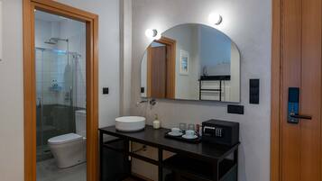Une salle de bain moderne avec une douche à parois de verre, un lavabo blanc, un grand miroir et un meuble-lavabo noir.
