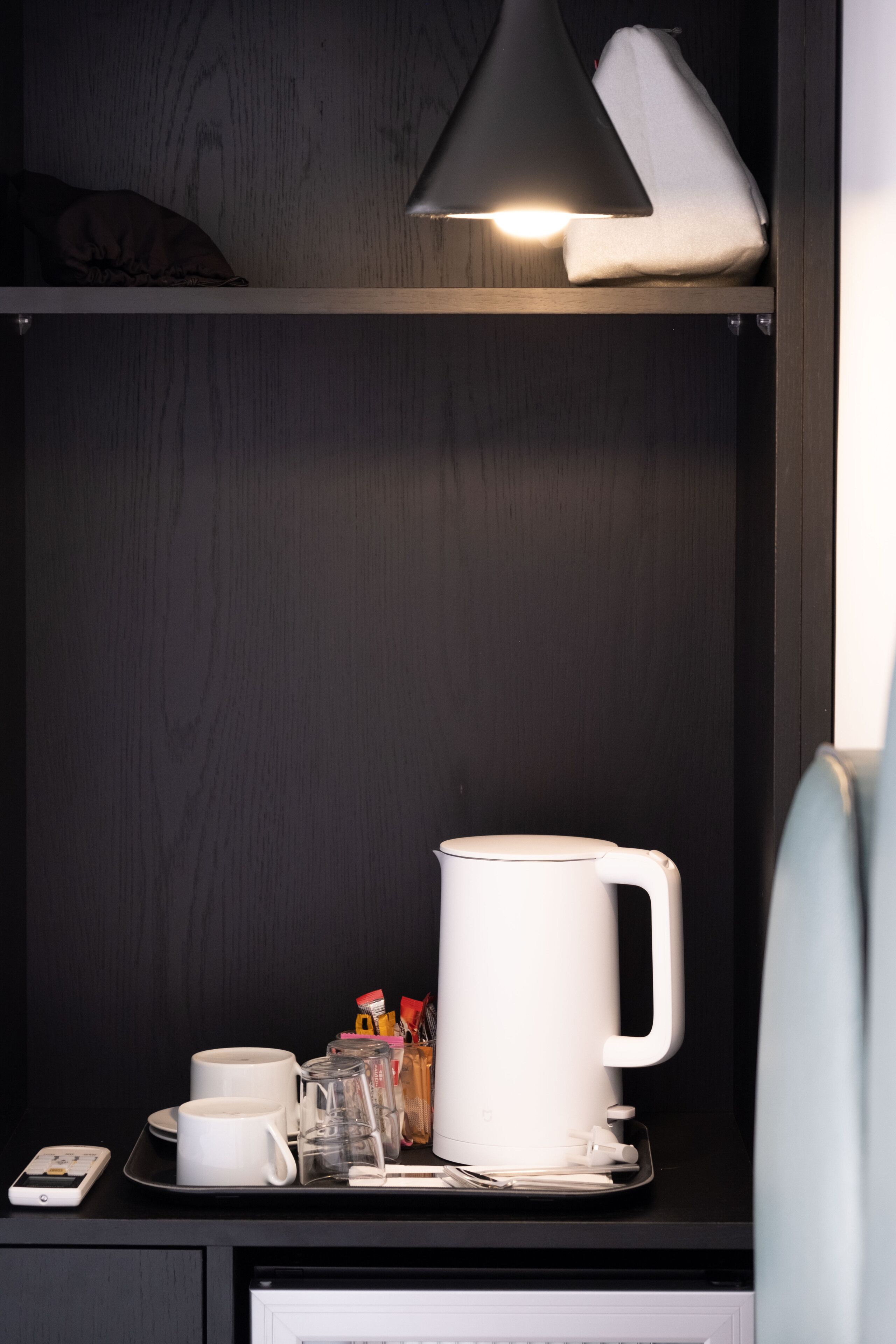 Ein ordentlich eingerichtetes Regal mit einer weißen Tasse, einer kleinen Ablage und einem Smartphone.