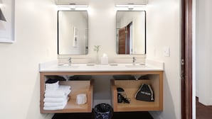 A modern bathroom with two sinks, a mirror, and a vanity with storage.