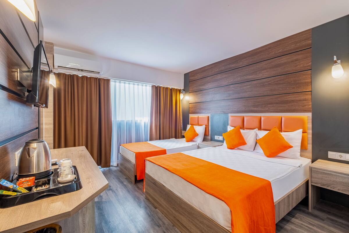 A hotel room with two beds, a coffee maker, and a TV on the wall.