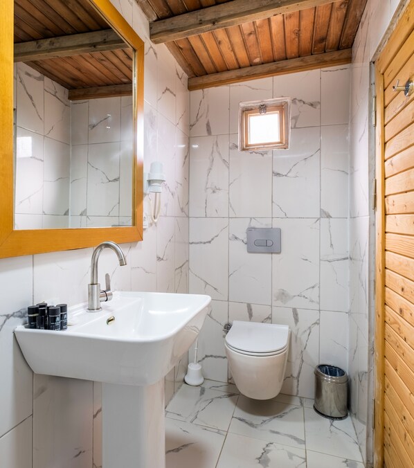 Un baño con lavamanos blanco, inodoro y espejo.