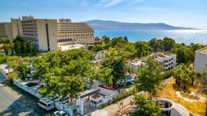 Un hotel con zona de piscina, rodeado de árboles y edificios, con vistas a una masa de agua.
