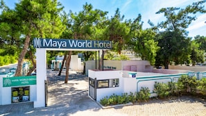 The entrance to the Maya World Hotel with a sign, a covered walkway, and a view of the surrounding trees.