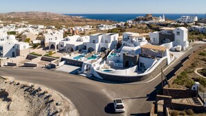 A coastal village with white buildings, a road, and a car. - Acro Blue Luxury Villas (Santorini)