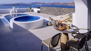 Una terraza en la azotea con jacuzzi, comedor y vista al mar.