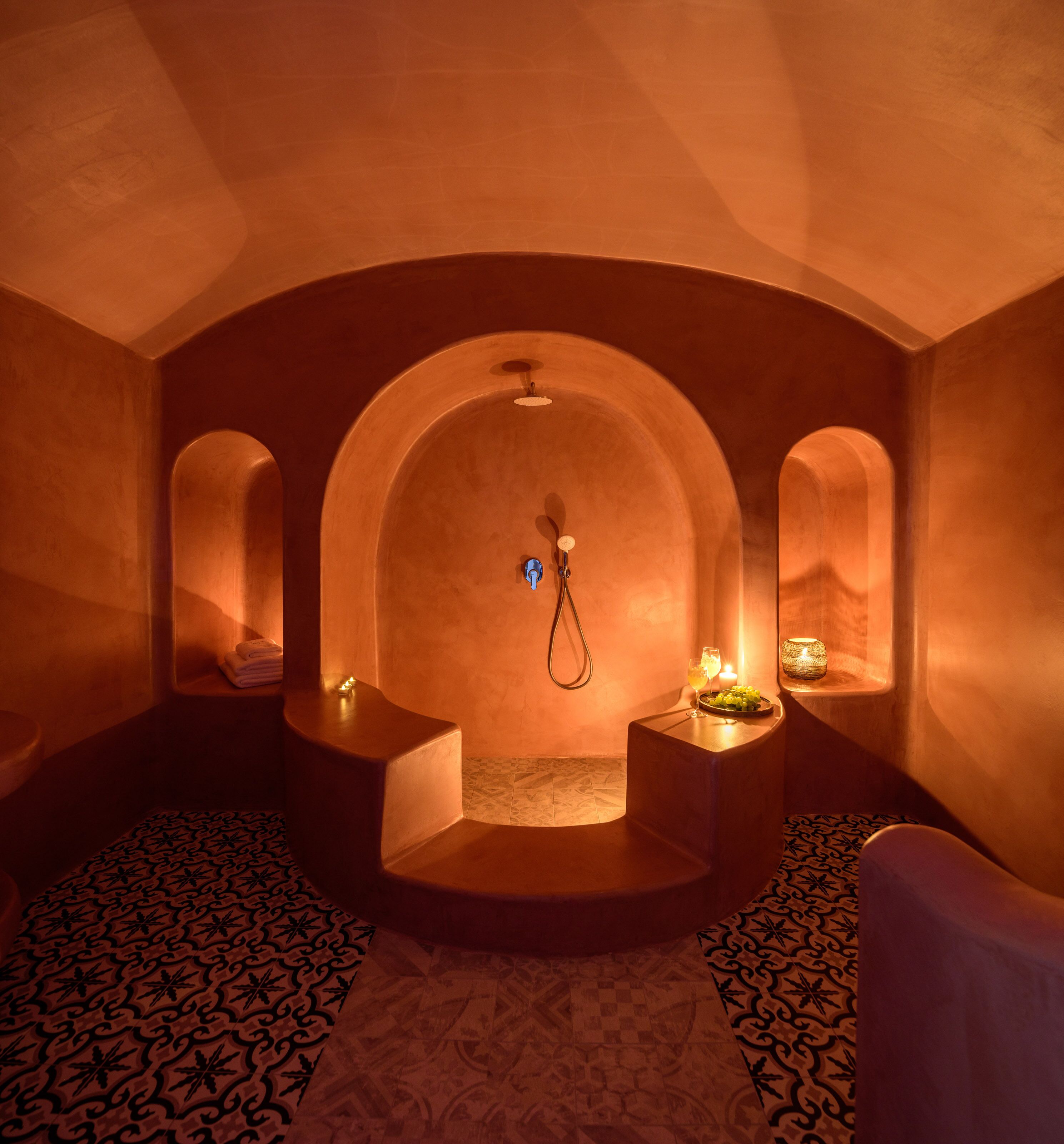A spa room with a central seating area, a massage table, and a small table with candles and a glass.
