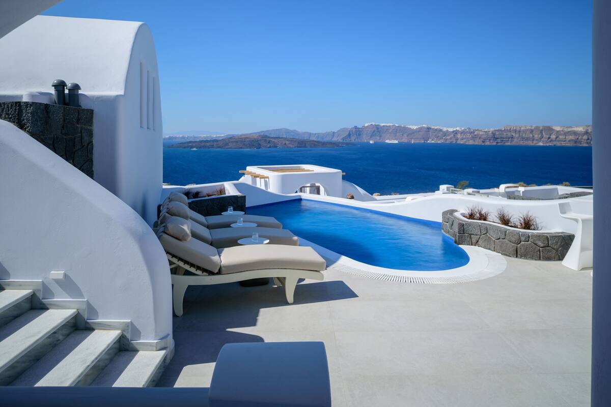 Uma área moderna com piscina ao ar livre, vista para o mar e falésias ao longe.