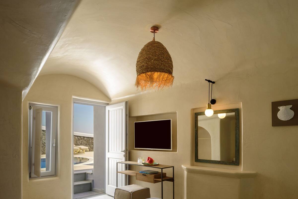 Quarto com cama, escrivaninha, televisão e vista para o exterior.