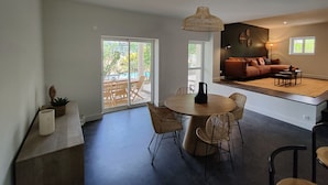 En moderne opholdsstue med spiseplads, sofa og udsigt til det fri.