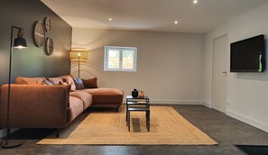 Relax in this stylish living room with a large sofa, floor lamp, and flat-screen TV.