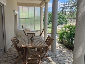 Relax in a serene outdoor space with a hammock, wooden table, and comfortable seating.