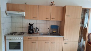 Une cuisine avec des meubles de rangement en bois, une cuisinière, une machine à café et un évier.