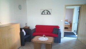 Un salon avec un canapé rouge, un meuble en bois et une petite table.