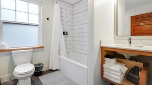 A bathroom with a toilet, shower, and sink.
