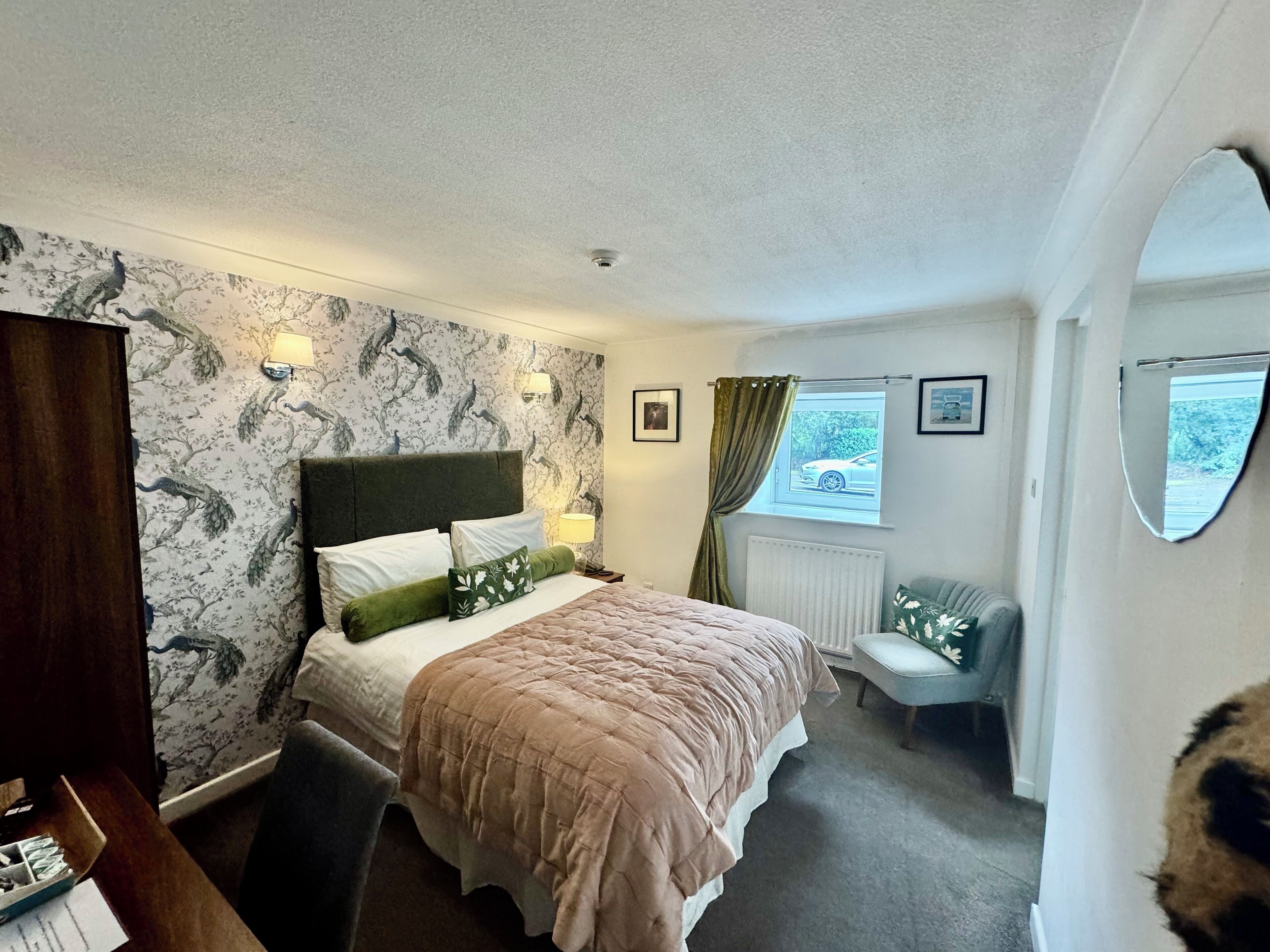 A bedroom with a bed, a desk, a chair, a window with curtains, and a radiator.