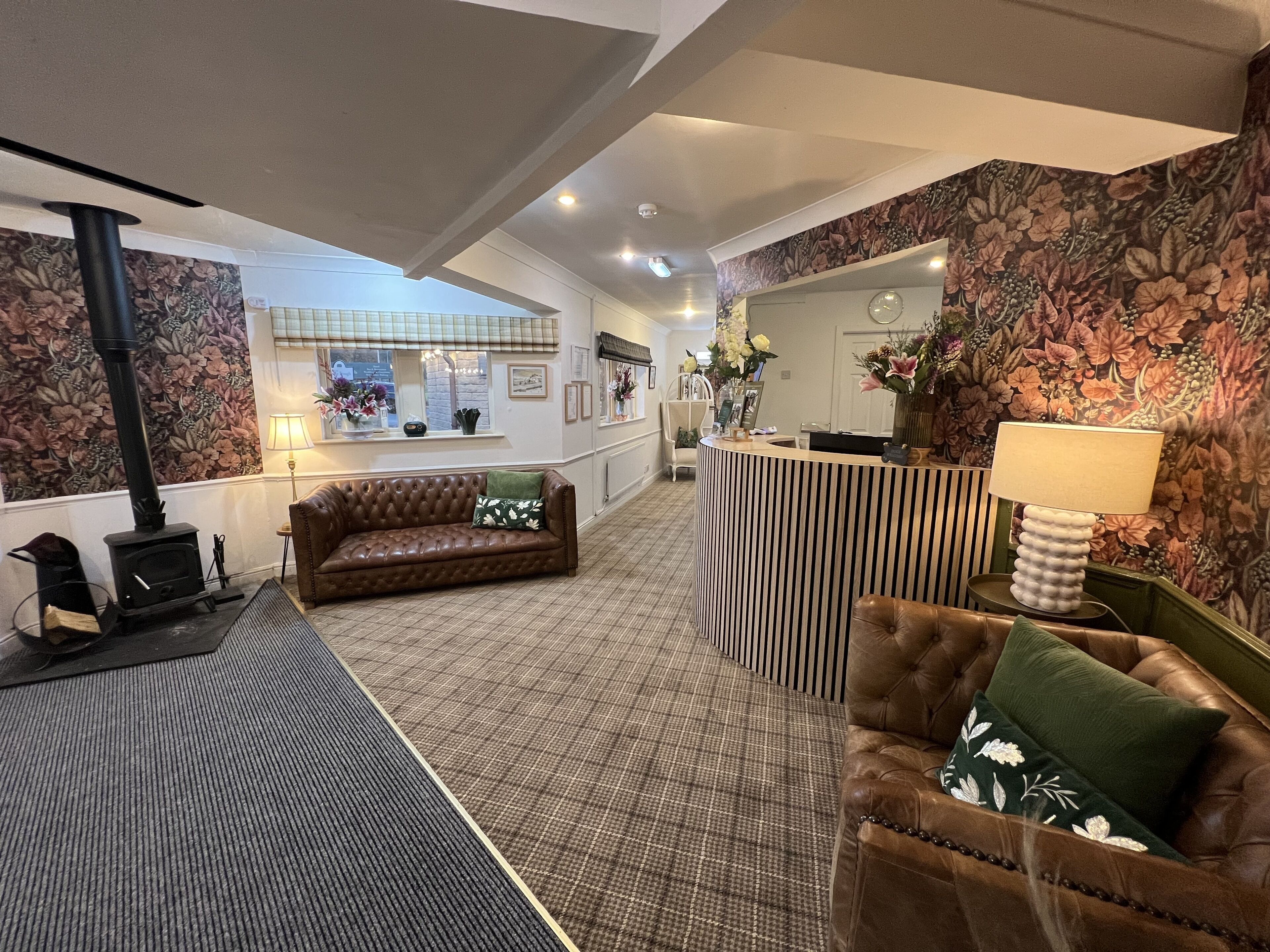 A lobby with a sofa, a chair, a reception desk, and a fireplace.