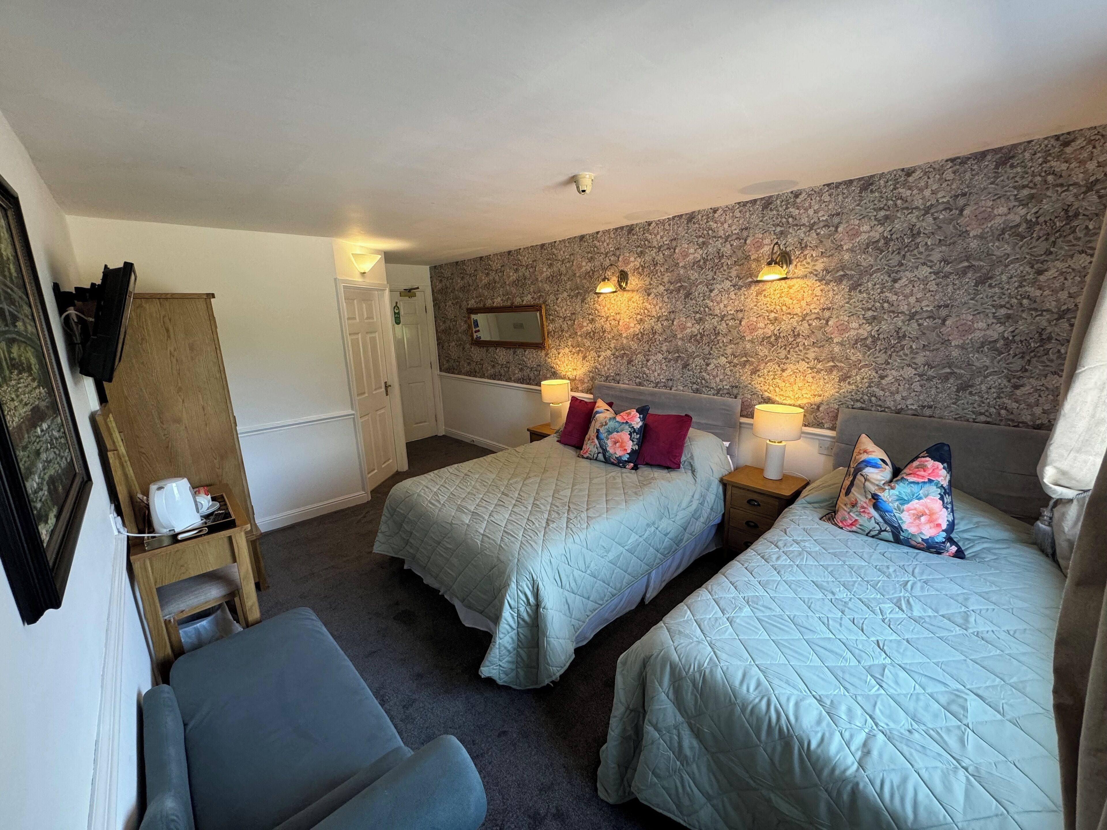A hotel room with two beds, a desk, and a chair.