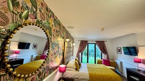 Habitación de hotel con dos camas, un espejo grande, un televisor y vistas al exterior.