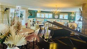 Un piano de cola en un salón amplio y elegantemente decorado, con asientos cómodos y vista al área del bar.