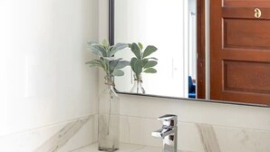 A bathroom with a white marble sink, a chrome faucet, and two clear glass vases with green plants. - Summit Lofts, 2 Queen Beds, Mt Shasta #201 (Mt Shasta)