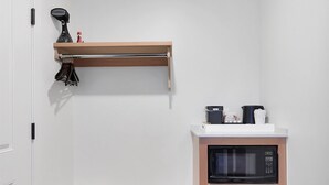 A compact kitchen with a built-in microwave and refrigerator, a wooden bench, and a shelf with a hairdryer and other small items. - Summit Lofts, 2 Queen Beds, Mt Shasta #201 (Mt Shasta)