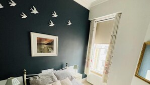 A bedroom with a bed, nightstands, a window with curtains, a chandelier, and wall decorations. - Charming 2-bedroom Apartment Located in Ayr (Ayr)
