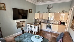 A living room with a brown leather sofa, a round coffee table, and a blue shaggy rug. - Charming 2-bedroom Apartment Located in Ayr (Ayr)
