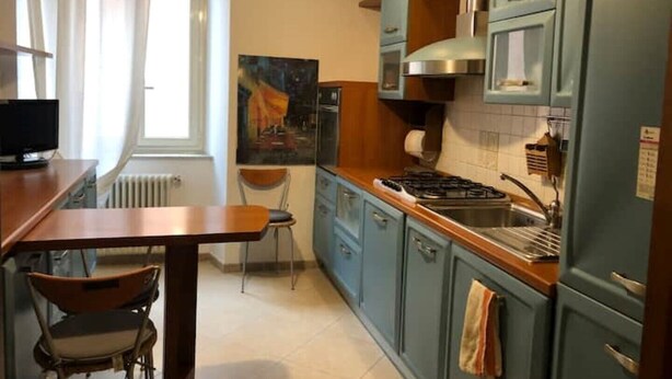 A compact kitchen with blue cabinets, a wooden countertop, and a stove.