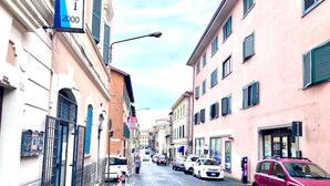 A narrow street lined with buildings, some with visible signage and others with barred windows.