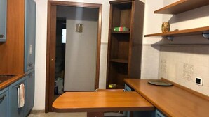 A compact kitchen with a wooden table, a chair, and built-in shelves.