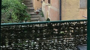 A narrow alley with a staircase leading to a building with multiple windows and a green tree.