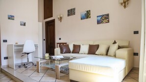 A modern living room with a sofa, a glass coffee table, and a white office chair. - Appartamento all'Arenaccia by Wonderful Italy (Napoli)