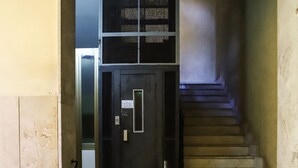 A staircase with a black door at the top, leading to a landing with a metal handrail and a tiled floor. - Appartamento all'Arenaccia by Wonderful Italy (Napoli)