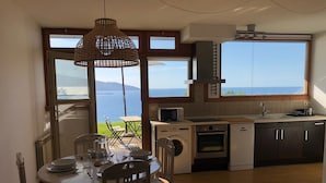 Une cuisine avec vue sur la mer, un coin repas avec une table et des chaises, et un lave-linge.