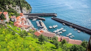 Une ville côtière dotée d’un port de plaisance, de bâtiments aux toits rouges et d’une colline abrupte.