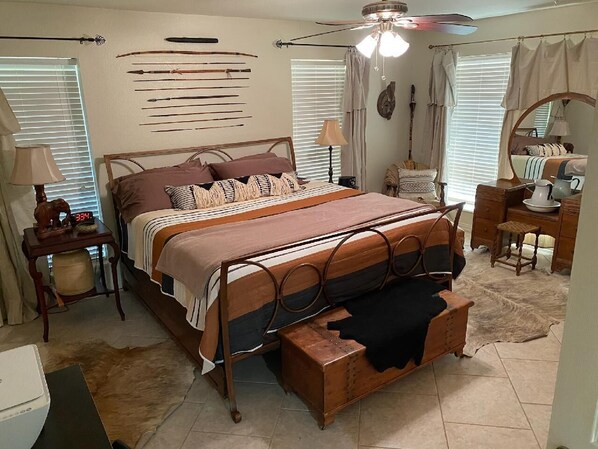 Un dormitorio con cama, mesita de noche, lámpara, espejo y ventana con persianas.