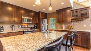 Eine moderne Küche mit Granit Arbeitsplatten, Edelstahlgeräten und dunklen Holzschränken.