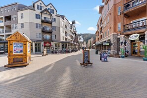 Un espacio peatonal empedrado con edificios de varios pisos, un quiosco de madera y un cartel.