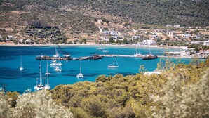 A coastal town with boats docked at a pier, surrounded by hills and buildings.